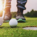 golf player putting golf ball into hole